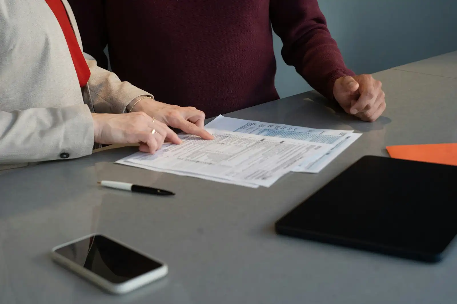 Two people at a table going over printed forms together